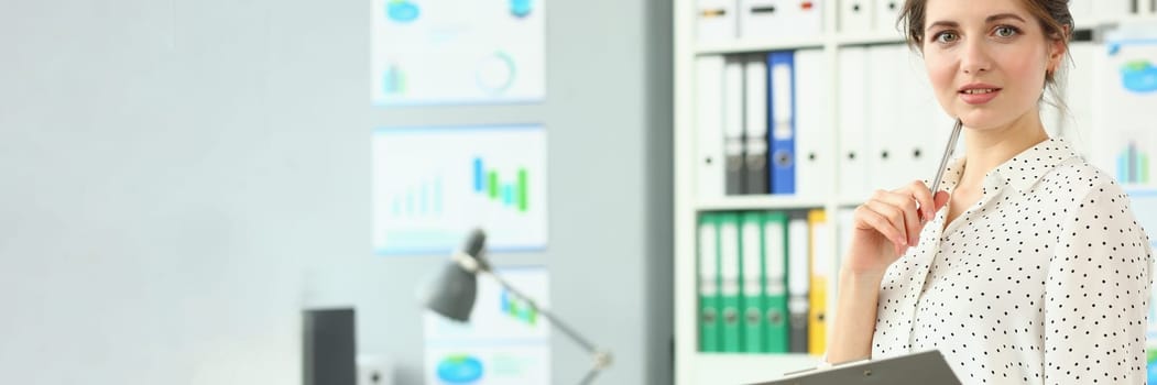 Portrait of smart pensive business woman holding pen and documents in office. Business consultant manager or boss