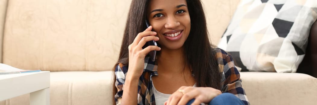 Happy positive beautiful black woman talking on mobile phone from home. Young beautiful afro woman enjoying talking on phone
