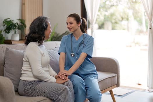 caregiver with senior woman and holding hands for care indoors. Retirement, consulting and professional female nurse with elderly person smiling together for healthcare support at nursing home.