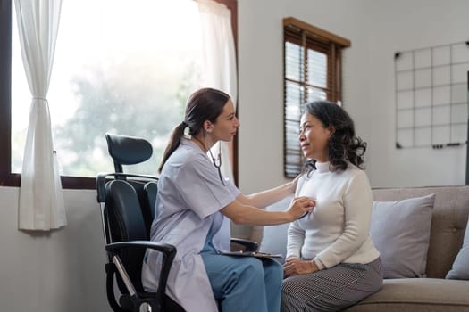 female caregiver visit smiling senior grandmother check heart rate, young woman doctor use statoscope do regular checkup of old lady patient at home, elderly healthcare concept.