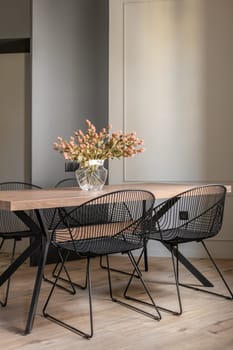An inviting living space filled with modern furniture and indoor plants. A wooden table and chairs sit in the dining room while flowers adorn the room.