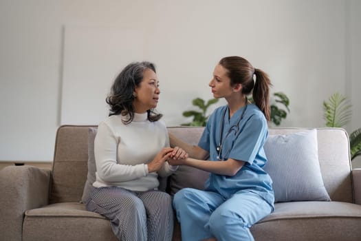 caregiver with senior woman and holding hands for care indoors. Retirement, consulting and professional female nurse with elderly person smiling together for healthcare support at nursing home.