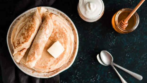 Stack of traditional russian pancakes blini on black background with copy space. Homemade russian thin pancakes blini. Russian food, russian kitchen. Top view or flat lay