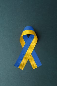 ukraine yellow blue ribbon in the middle of green table. concept needs help and support, truth will win