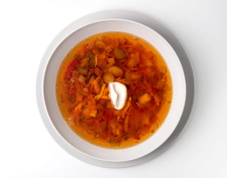 Bowl with chicken, beetroot and other vegetables soup. Perfect bright broth in italian minestrone style, isolated on white. Top view or flat lay.
