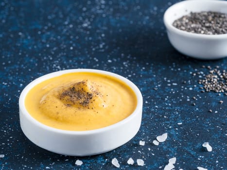 Creamy Cheddar sauce with chia seeds on dark background.Ideas and recipe for healthy diet or vegan food.Homemade Chia Cheeze Sauce for snacks,tacos,nachos,dipping,mac-n-cheese,base for pizza.Copyspace