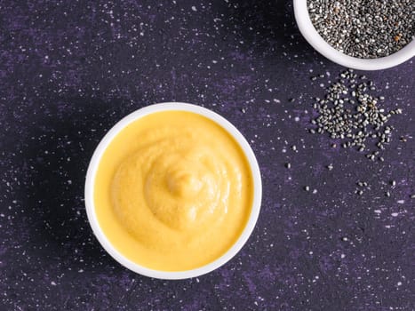 Creamy Cheddar sauce with chia seeds on dark background.Ideas and recipe for healthy diet or vegan food.Homemade Chia Cheeze Sauce for snacks,tacos,nachos,dipping,mac-n-cheese,base for pizza.Copyspace