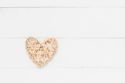 A wooden wicker heart on white table background with copy space for love and Valentine's day concept