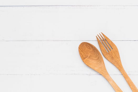 Top view of wooden spoon and fork on white table background for utensil and kitchenware concept