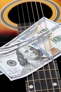 Dollar bills on an acoustic guitar close up