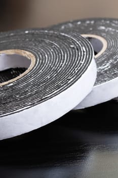 Three reels of double-sided tape on a wooden table