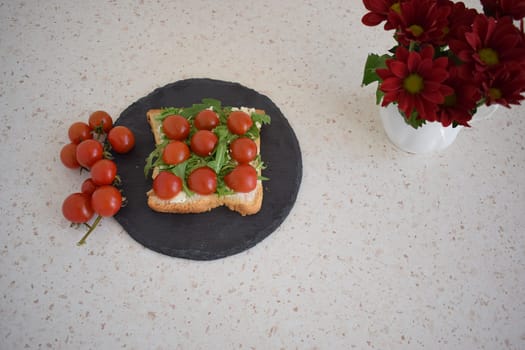 Healthy toast for breakfast with tomatoes, arugula and herbs.