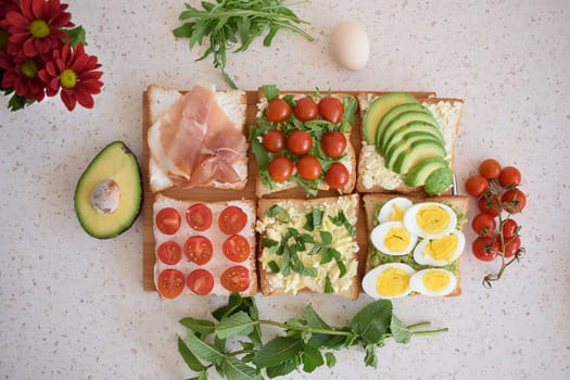 Healthy toast for breakfast with avocado, eggs, tomatoes, arugula etc.