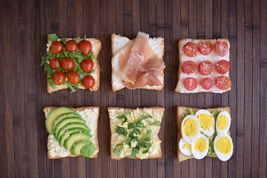 Healthy toast for breakfast with avocado, eggs, tomatoes, arugula etc.