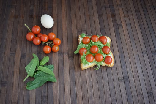 Healthy toast for breakfast with tomatoes, arugula and herbs.