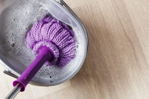 Purple mop in a bucket of water. The concept of indoor cleaning.copy space.