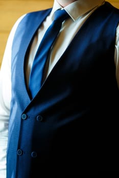 Man puts on a wedding suit and accessories on the wedding day.