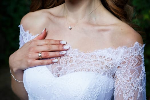 Bride's hands folded on a white wedding dress