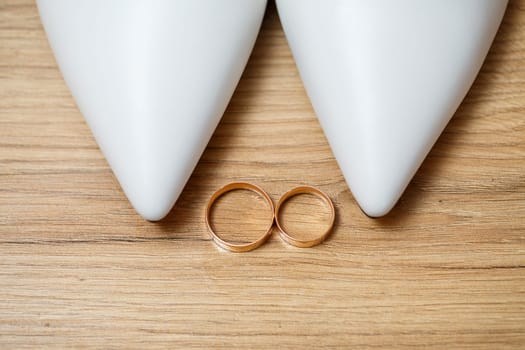 Golden rings of the newlyweds between white shoes with heels. Precious rings of the bride and groom