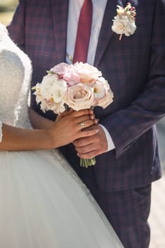 Wedding bouquet with fresh natural flowers in the hands of the bride