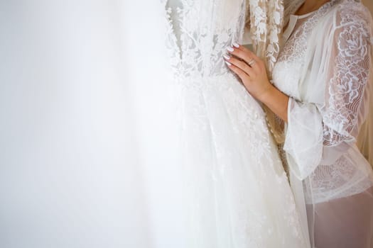 the bride holds in her hands a beautiful wedding dress