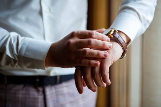 Man puts on a wedding suit and accessories on the wedding day.