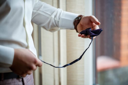 Man puts on a wedding suit and accessories on the wedding day.