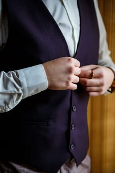 Man puts on a wedding suit and accessories on the wedding day.