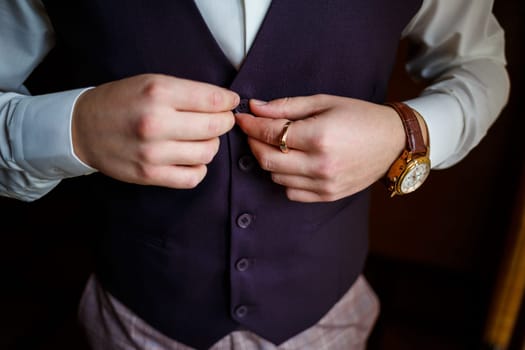 Man puts on a wedding suit and accessories on the wedding day.