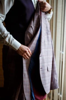 Man puts on a wedding suit and accessories on the wedding day.