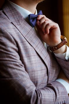 Man puts on a wedding suit and accessories on the wedding day.