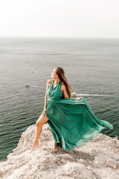 Woman sea trevel green dress. Side view a happy woman with long hair in a long mint dress posing on a beach with calm sea bokeh lights on sunny day. Girl on the nature on blue sky background