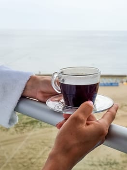 White coffee mug in man hand on terrace overlooking sea or ocean. Enjoying morning coffee on paradise island