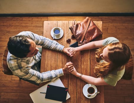 Top view, couple and holding hands in cafe, celebration and relax together, Valentines day and romance. Romantic, man and woman with love, coffee shop and talking for relationship, loving and bonding.