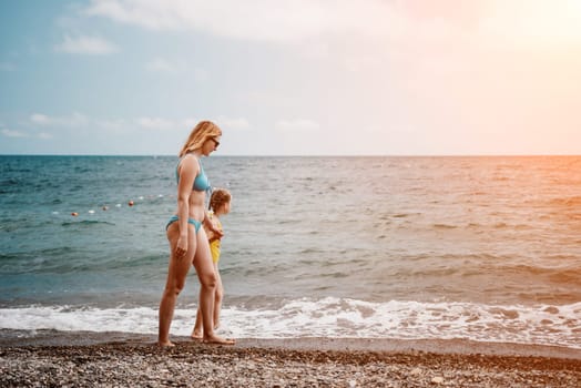 Happy loving family mother and daughter having fun together on the beach. Mum playing with her kid in holiday vacation next to the ocean - Family lifestyle and love concept.