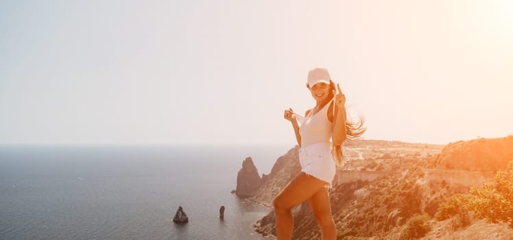 Woman travel sea. Young Happy woman in a long red dress posing on a beach near the sea on background of volcanic rocks, like in Iceland, sharing travel adventure journey