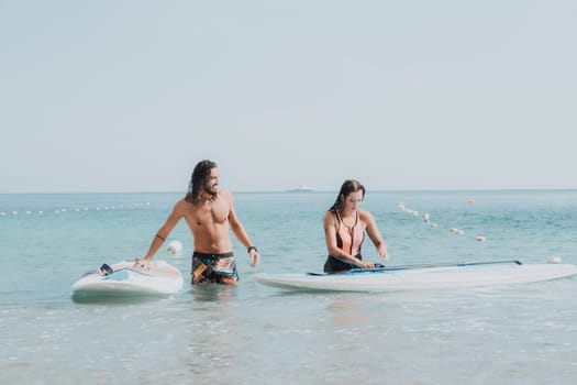 Woman man sea sup. Close up portrait of beautiful young caucasian woman with black hair and freckles looking at camera and smiling. Cute woman portrait in a pink bikini posing on sup board in the sea