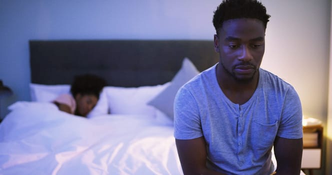 Black couple, bedroom and man with a problem at night while thinking of divorce, stress or depression. A woman sleeping in bed at home with partner upset about fight, marriage or erectile dysfunction.