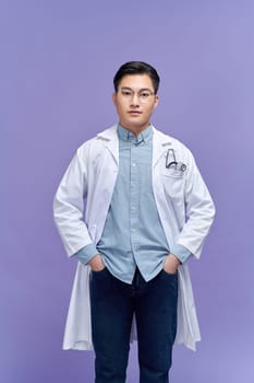 Portrait of beautiful young female doctor in white medical jacket isolated on purple background.