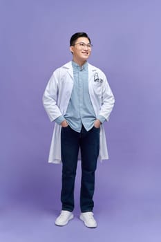 Portrait of beautiful young female doctor in white medical jacket isolated on purple background.