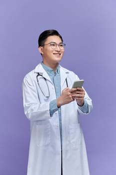 Portrait of attractive young medical doctor with stethoscope working in clinic and holding cellphone