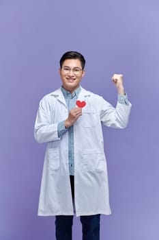 doctor man holding red heart at the clinic screaming proud with raised arm