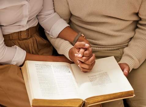 Bible, holding hands and reading with a black couple together in the home for religion, faith or belief in God. Jesus, pray or book with a christian man and woman learning about the spiritual christ.