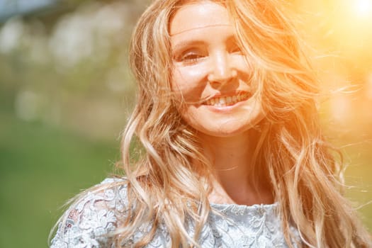 Portrait of a blonde in the park. Happy woman with long blond hair in a blue dress