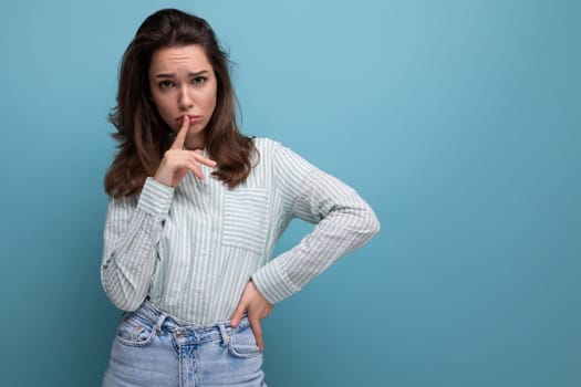 embarrassed 25s woman with black hair in casual clothes on studio background with copy space.