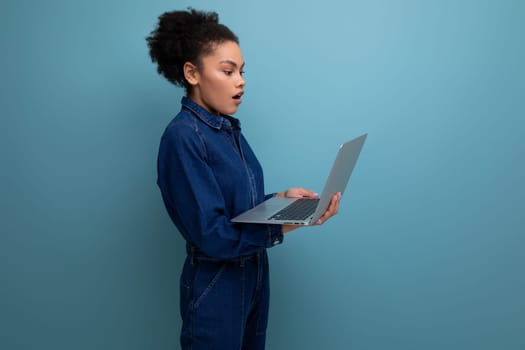 young pretty brunette latin woman with afro ponytail dressed in denim clothes working using laptop.