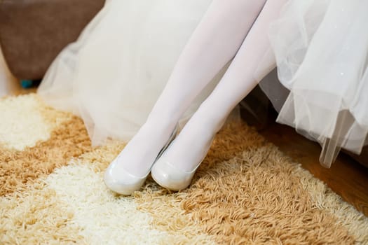 Bride puts white shoes on her legs