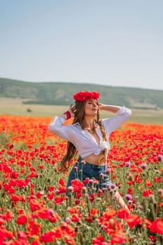 Happy woman in a poppy field in a white shirt and denim skirt with a wreath of poppies on her head posing and enjoying the poppy field