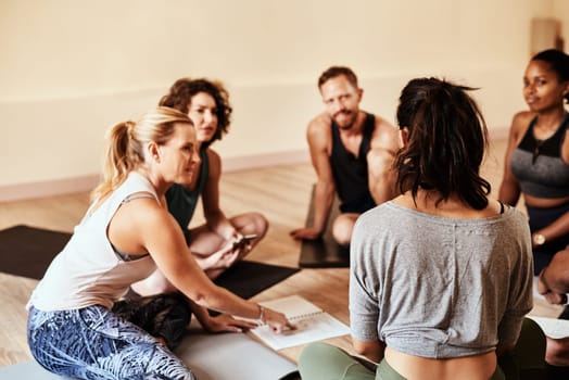 Friends who do yoga together grow together. a group of young men and women chatting during a yoga class