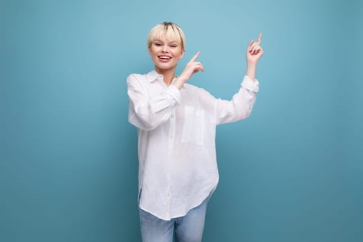 cheerful young blond business woman in a white shirt reports interesting news on the background with copy space.